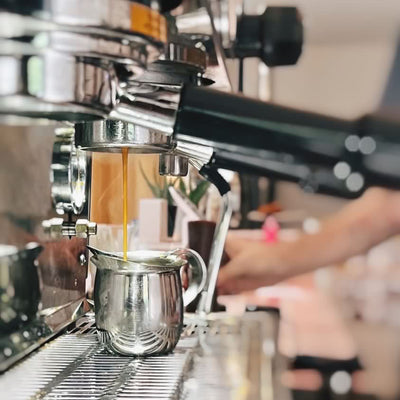 Espresso being brewed into a portafilter with a blurred background at Loveless Cafe